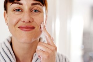 mujer aplicando crema facial en su cara